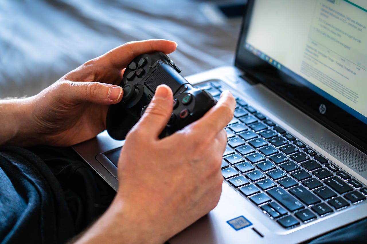 journey-01 Person holds a gaming controller while interacting with a laptop, emphasizing modern gaming technology.