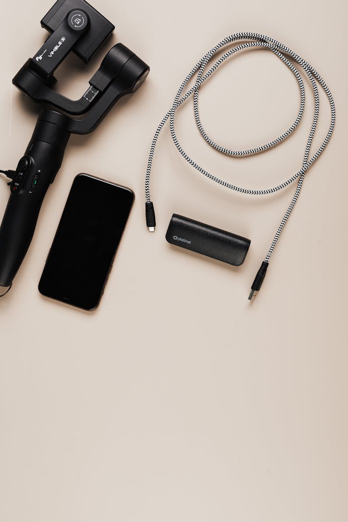 services-04 Minimalist flat lay featuring a smartphone, gimbal, charging cables, and power bank on a beige background.